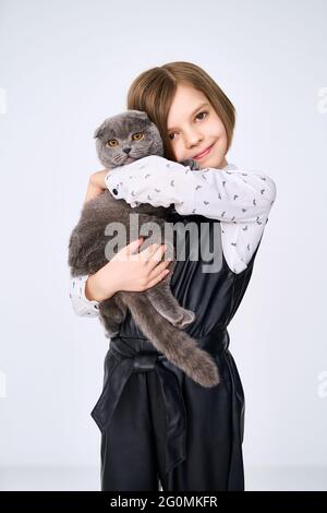 La bambina caucasica tiene il suo gatto tra le braccia Foto Stock