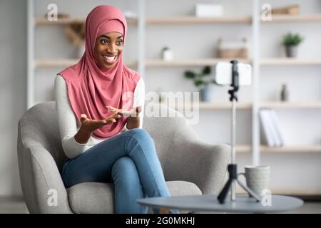 Concetto di Blogging moderno. Black Muslim Lady in Hijab registrazione video a casa Foto Stock