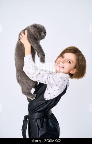 La bambina caucasica tiene il suo gatto tra le braccia Foto Stock