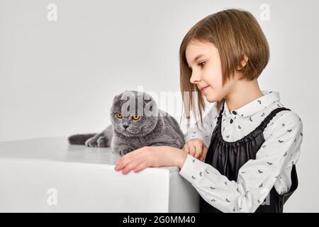 La bambina caucasica tiene il suo gatto tra le braccia Foto Stock