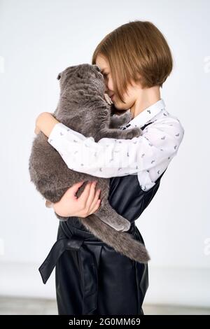 La bambina caucasica tiene il suo gatto tra le braccia Foto Stock