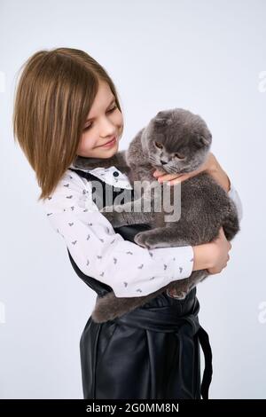 La bambina caucasica tiene il suo gatto tra le braccia Foto Stock