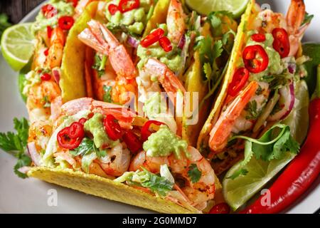 conchiglie di taco con gamberi, insalata di cavolo, lime e guacamole su un piatto, primo piano Foto Stock