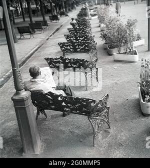 Negli anni '50. Una lunga fila di panchine si trova nel parco Kungsträdgården di Stoccolma. Un uomo sulla panchina più vicina è seduto e sta leggendo il giornale. Svezia 1953 rif BL97-3 Foto Stock