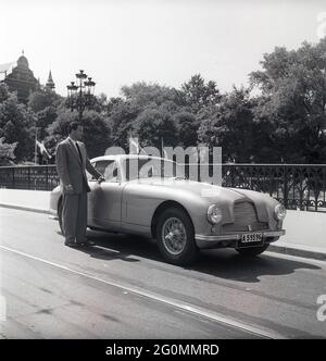 Guida negli anni '50. Un uomo accanto alla sua auto, un Aston Martin DB2. Questo modello è stato presentato nel 1950 ed è stato prodotto in 411 vetture. Aveva un motore a sei cilindri, quattro marce e un chassi progettato da Frank Feeley. Svezia 1953. rif BL108-9 Foto Stock