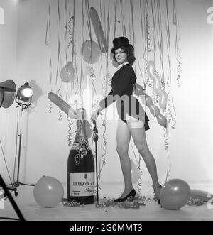 Champagne negli anni '50. Una giovane donna in una scena che chiaramente è destinata a suggerire qualcosa da celebrare. Una bottiglia gigante di champagne Delck fa parte dell'arredamento, palloncini e confetti appesi sullo sfondo. Svezia 1952 rif BK84-1 Foto Stock