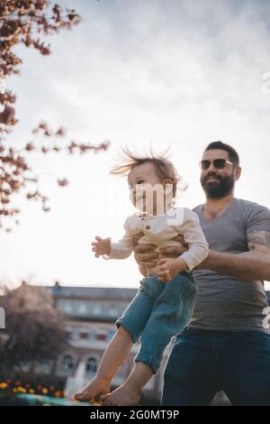 Il padre getta il suo bambino nell'aria. Foto Stock