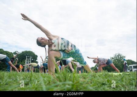 Un gruppo di persone che fanno una lezione di yoga e si esercitano in un festival all'aperto in un campo.