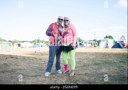 Un gruppo di amici e persone vestite al neon in una festa estiva in un campo. Foto Stock