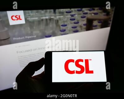 Persona che detiene smartphone con il logo della società farmaceutica australiana CSL Limited sullo schermo di fronte al sito web. Mettere a fuoco il display del telefono. Foto Stock