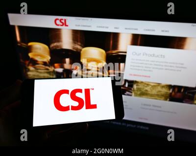 Persona che tiene il cellulare con il logo della società farmaceutica australiana CSL Limited sullo schermo di fronte alla pagina web aziendale. Mettere a fuoco il display del telefono. Foto Stock