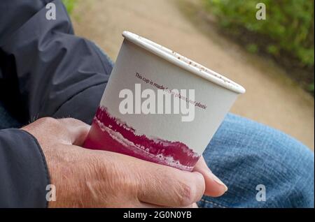 Primo piano di una persona che tiene in mano bevande alcoliche usa e getta contenitore di bicchieri prodotto da piante Inghilterra Regno Unito Regno Unito Gran Bretagna Foto Stock