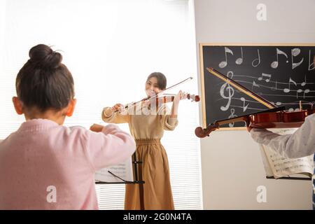 Le giovani donne insegnano ai bambini lezioni di musica Foto Stock