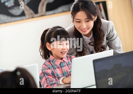 L'insegnante che consiglia i bambini usa il computer Foto Stock