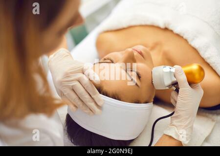 Mani di cosmetologa che fa drenaggio linfatico del viso per la donna in salone termale Foto Stock