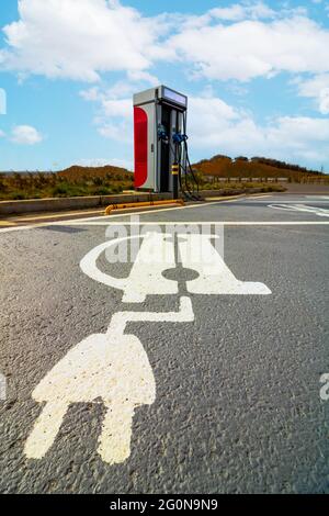 Stazione di ricarica per veicoli elettrici senza auto e parcheggi con icone di ricarica per veicoli elettrici. Energia alternativa per le auto moderne. Vetture a emissioni zero. Veicoli elettrici ch Foto Stock