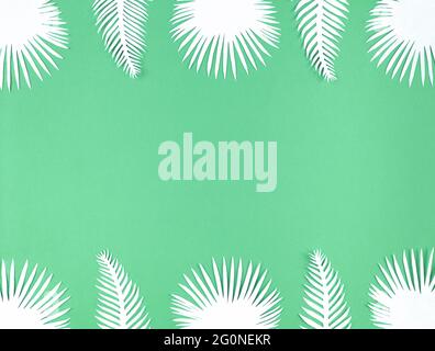 Foglie di carta tropicale su sfondo verde, giacitura piatta con spazio per la copia. Foto Stock