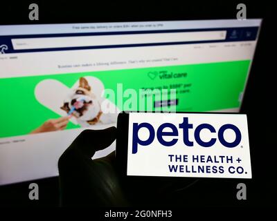 Persona che detiene il telefono cellulare con il logo del rivenditore Petco Health and Wellness Company Inc. Sullo schermo davanti alla pagina web. Mettere a fuoco il display del telefono. Foto Stock