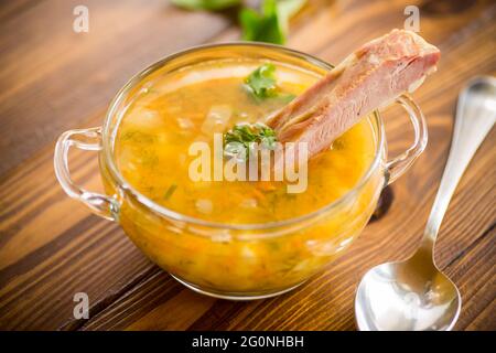 zuppa di piselli cotti con costolette affumicate in un piatto Foto Stock