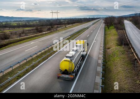 Carro armato isotermico che guida in autostrada. Trasporto e logistica di petrolio e gas. Cisterna cromata in metallo con prodotti petrolchimici. Liquido C Foto Stock