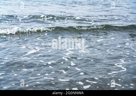 Onde sul mare con sabbia nera Foto Stock