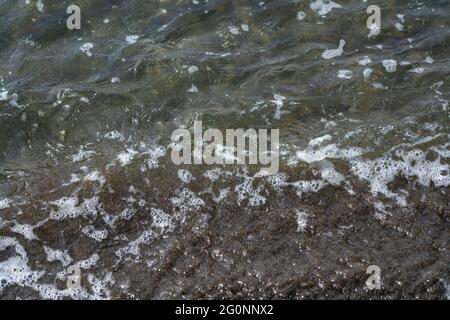 Onde sul mare con sabbia nera Foto Stock