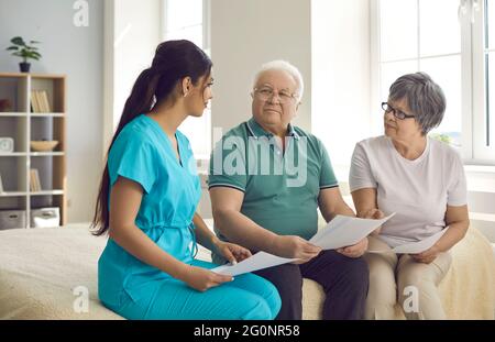 L'operatore sanitario professionale aiuta i pazienti anziani a comprendere e compilare il contratto di assistenza domiciliare Foto Stock