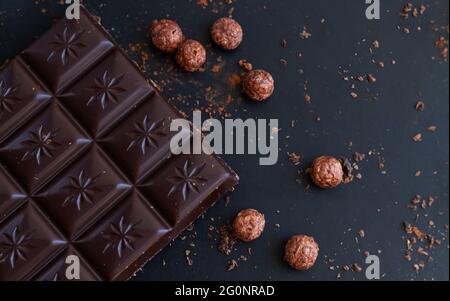 Deliziosa barra di cioccolato fondente con trucioli, briciole, palle di riso vista dall'alto sul tavolo dell'ardesia Foto Stock