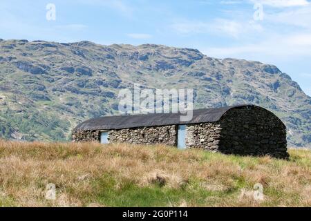 Vecchio edificio in pietra con tetto in metallo ondulato ricurvo vicino a Loch Katrine, Trossachs, Scozia, Regno Unito Foto Stock