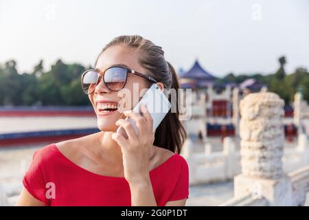 Donna asiatica felice che parla con qualcuno al telefono. Ragazza che chiama con l'app mobile durante i viaggi estivi in cina Foto Stock