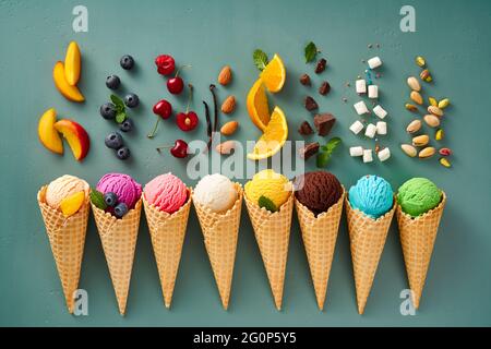 Assortimento di gelato in coni su sfondo blu. Set colorato di gelato di sapori diversi. Gelato isolato con noci, frutta e bacche. Foto Stock