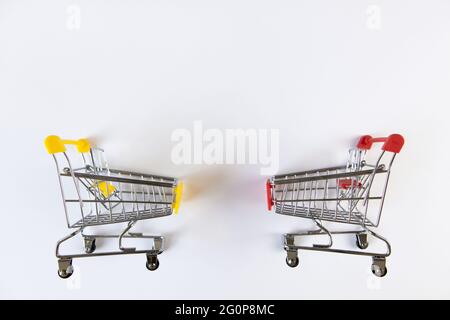 Due piccoli carrelli decorativi vuoti con accenti gialli, rossi su sfondo bianco, posto per il testo. Vista dall'alto. Mockup, spazio di copia. Concetto b Foto Stock