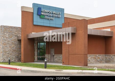 Lompoc, CA, USA - 26 maggio 2021: Emblema bianco su blu del Lompoc Valley Medical Center sulla sommità dell'entrata dipinta di marrone dell'edificio principale. Foto Stock