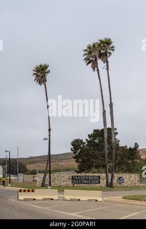 Lompoc, CA, USA - 26 maggio 2021: Ritratto, Vandenberg Space Force base ingresso visto da strada con emblema, palme e piante, strada gialla barrie Foto Stock