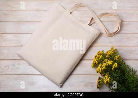 Borsa tote in tela mockup con fiori gialli selvatici. Borsa rustica dello shopping in lino mock up per la presentazione di branding Foto Stock