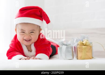 Bambino asiatico in Babbo Natale vestito su letto bianco per il giorno di Natale e felice festa di nuovo anno Foto Stock