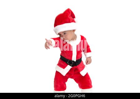 Bambino asiatico in un costume di Natale Babbo Natale che punta le dita e mostra qualcosa di sorprendente sul fronte isolato su sfondo bianco, scioccato, sur Foto Stock