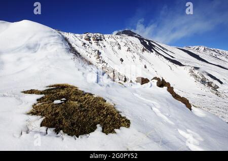 Il ripido pendio di montagna della Valle del Bove coperto di neve in Sicilia sotto il cratere sud-est dell'Etna Foto Stock