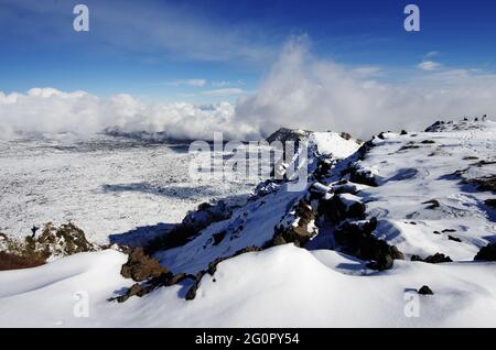 Neve bianca e basse nuvole sul paesaggio della cresta rocciosa 'Salifizio' e della Valle 'Bove' in Sicilia un punto di riferimento del turismo all'aperto nel Parco dell'Etna Foto Stock