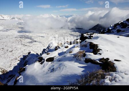 Neve bianca e basse nuvole sul paesaggio della cresta rocciosa 'Salifizio' e della Valle 'Bove' in Sicilia un punto di riferimento del turismo all'aperto nel Parco dell'Etna Foto Stock