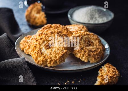 Biscotti dolci al cocco. Gustosi biscotti con sapore di cocco sul piatto sul tavolo nero. Foto Stock
