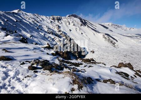 Il ripido pendio di montagna della Valle del Bove coperto di neve in Sicilia sotto il cratere sud-est dell'Etna Foto Stock