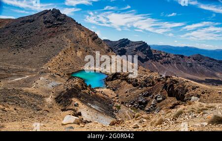 Guardando dal cratere rosso a uno dei tre laghi di Smeraldo sul valico alpino di Tongariro nell'altopiano centrale della Nuova Zelanda Foto Stock