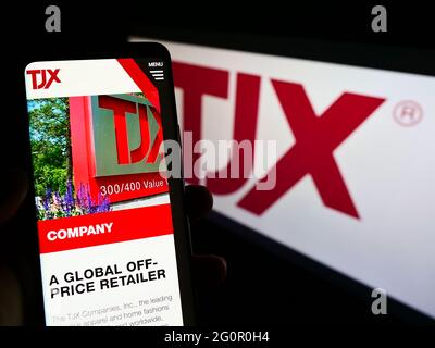 Persona che tiene il telefono mobile con il sito web della società US Department Store le società TJX Inc sullo schermo con il logo. Mettere a fuoco il centro del display del telefono. Foto Stock