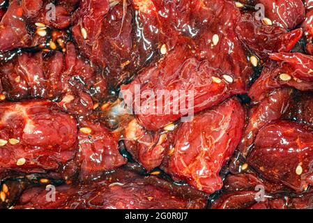Fette di manzo marinate, luminose e succose, con spezie, olio e semi di sesamo Foto Stock