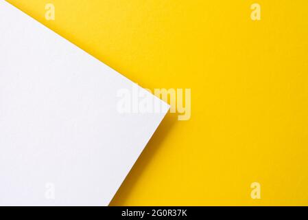 Carta di colore giallo e bianco con ombre come sfondo, vista dall'alto, spazio per il testo, disposizione piatta Foto Stock