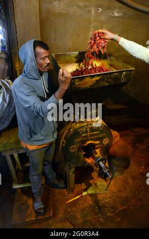 Macinare il peperoncino rosso al mercato delle spezie al Karwan Bazar a Dhaka, Bangladesh. Foto Stock