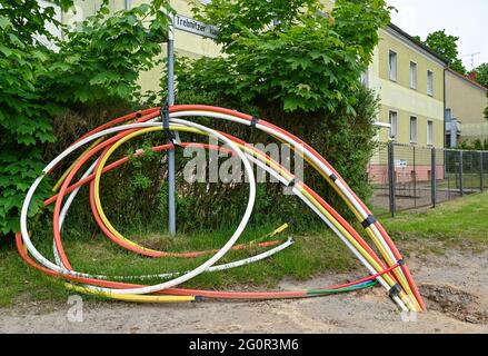 Trebnitz, Germania. 02 giugno 2021. Tubi vuoti colorati, nei quali saranno successivamente posati cavi in fibra ottica, sporgono dal suolo lungo una strada. Molte aziende locali stanno lanciando campagne di espansione per le connessioni Internet in fibra ottica. A questo scopo vengono posate nuove linee. Ciò che è già standard nelle città più grandi è ancora un sogno pipe per molti residenti rurali: Internet veloce. Sono stati spesi miliardi per spianare la strada all'era digitale anche nelle aree rurali. Ma in molti casi, i progressi sono lenti. Credit: Patrick Pleul/dpa-Zentralbild/ZB/dpa/Alamy Live News Foto Stock