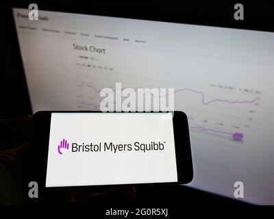 Persona che detiene smartphone con il logo della società farmaceutica statunitense Bristol Myers Squibb (BMS) sullo schermo di fronte al sito web. Mettere a fuoco il display del telefono. Foto Stock