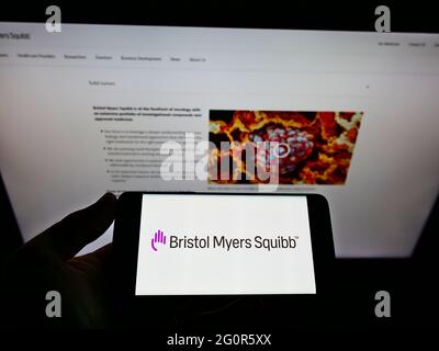 Persona che tiene il telefono mobile con il logo della società farmaceutica statunitense Bristol Myers Squibb (BMS) sullo schermo davanti alla pagina web. Mettere a fuoco il display del telefono. Foto Stock